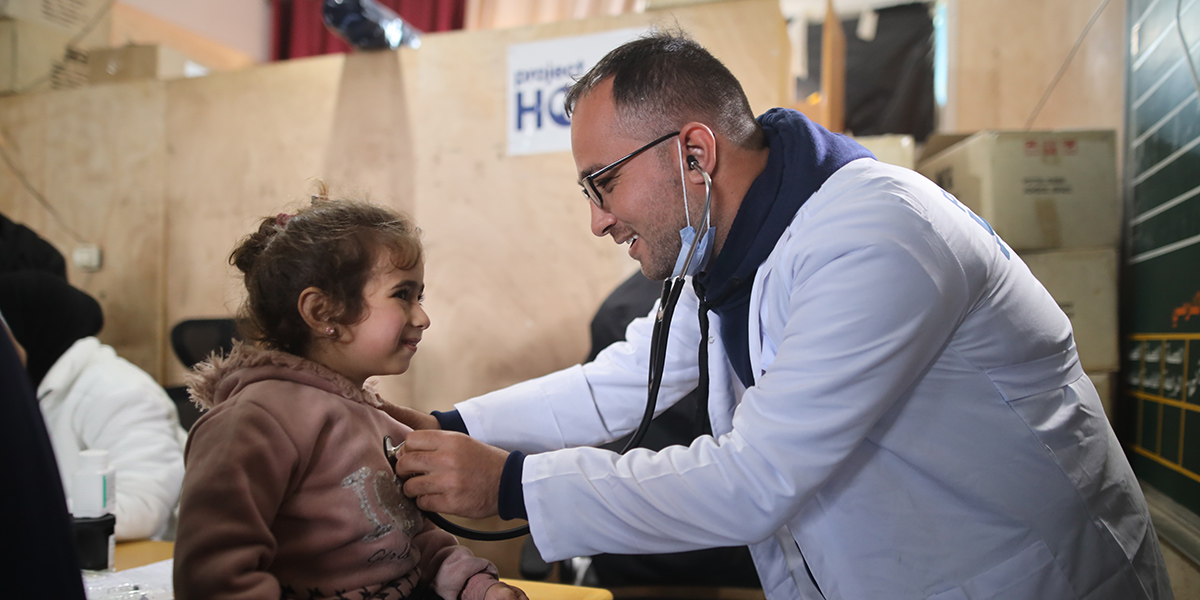 Photo of health worker in Gaza using a stethoscope to check a child's breathing and heart rate.